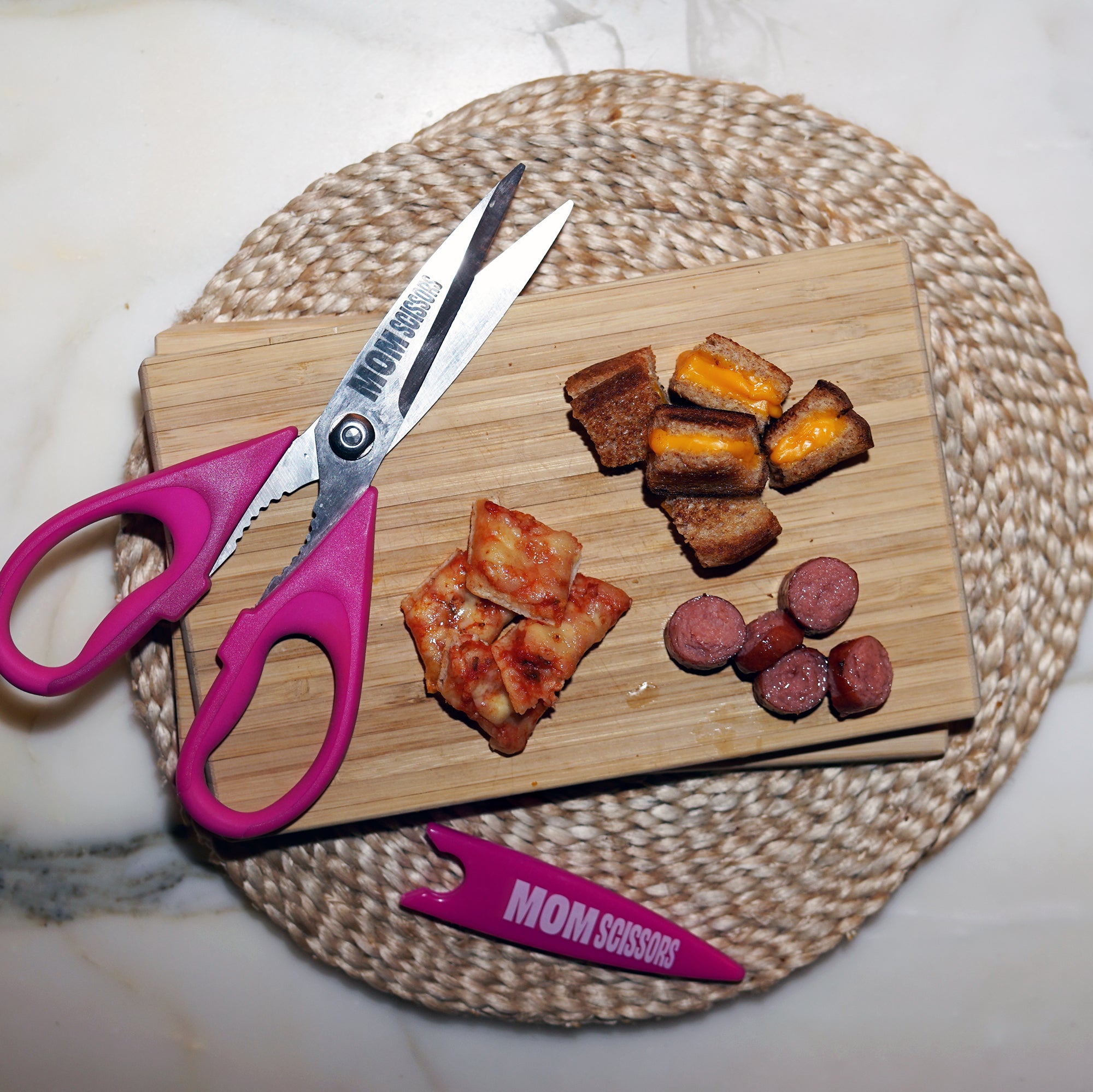 Mom Scissors alongside cut-up grilled cheese, pizza, and hot dogs—pink food scissors designed for toddlers and babies. Perfect for parents seeking pink baby food scissors or pink food scissors for toddlers to make mealtime quick, easy, and fun.