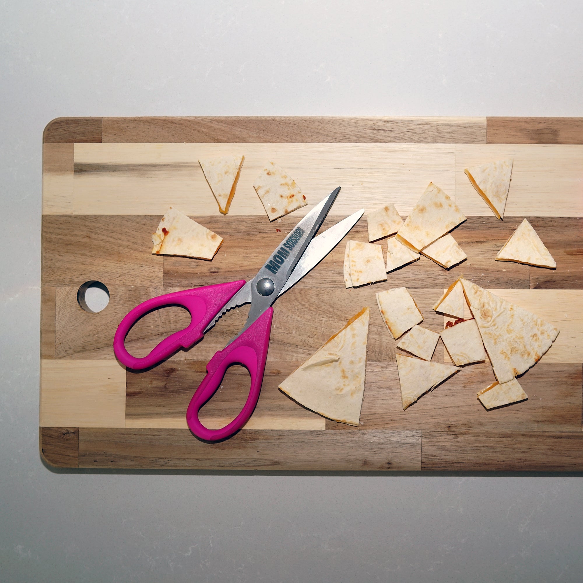 Mom Scissors cutting a quesadilla into bite-sized pieces—pink food scissors designed for toddlers and babies. Ideal as pink baby food scissors or pink food scissors for parents to make mealtime simple and fun.